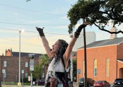 Woman in bohemian attire celebrating on Galveston street during ghost tour.